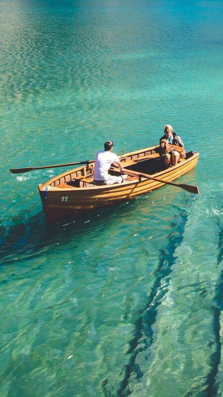 Mobile-sized portrait image, showing just one boat in the lake